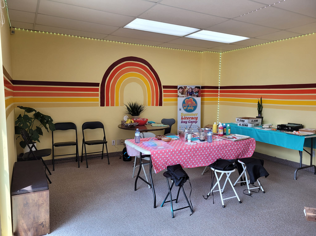 a room with tables and chairs in front of a rainbow painted wall for a paint class